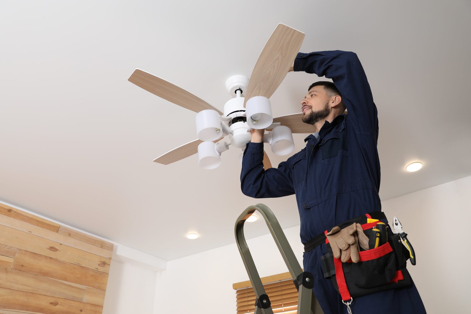 Electrician repairing ceiling fan with lamps indoors. Space for