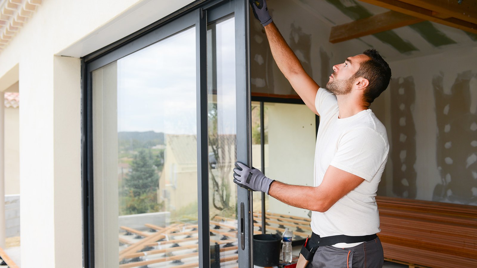 handsome young man installing bay window in a new house construction site