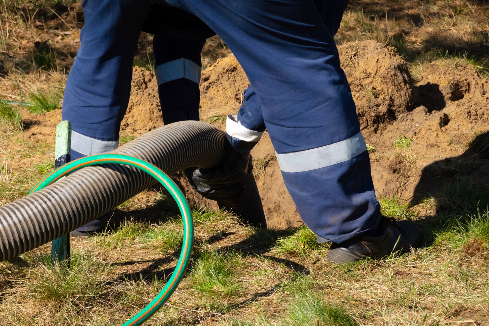 Man worker holding pipe, providing sewer cleaning service outdoo